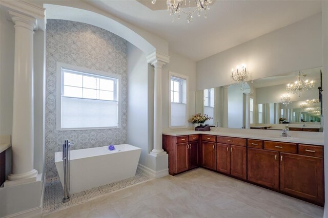 bathroom with vanity, a tub, an inviting chandelier, and ornate columns