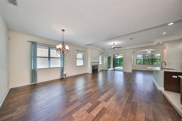 unfurnished living room with sink, ceiling fan with notable chandelier, dark hardwood / wood-style flooring, and a textured ceiling