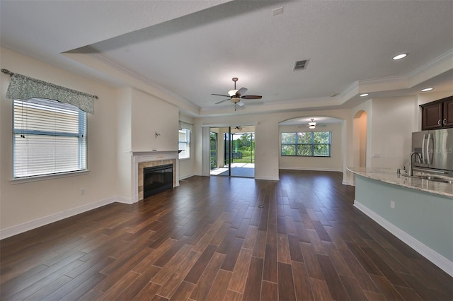 unfurnished living room with dark hardwood / wood-style flooring, ornamental molding, ceiling fan, sink, and a fireplace