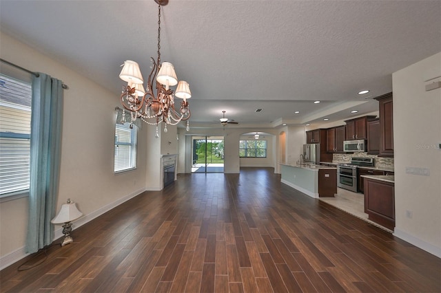 kitchen with dark brown cabinetry, dark hardwood / wood-style flooring, hanging light fixtures, and appliances with stainless steel finishes