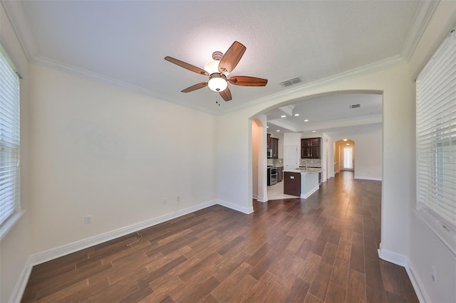 unfurnished living room featuring dark hardwood / wood-style floors, ceiling fan, and ornamental molding