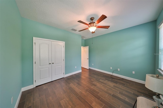 unfurnished bedroom with a closet, ceiling fan, dark hardwood / wood-style flooring, and a textured ceiling