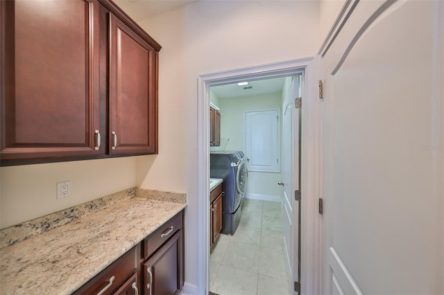 kitchen featuring washer and dryer, light stone counters, and light tile patterned flooring