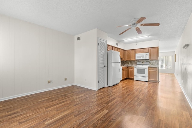 kitchen with hardwood / wood-style floors, white appliances, ceiling fan, and backsplash