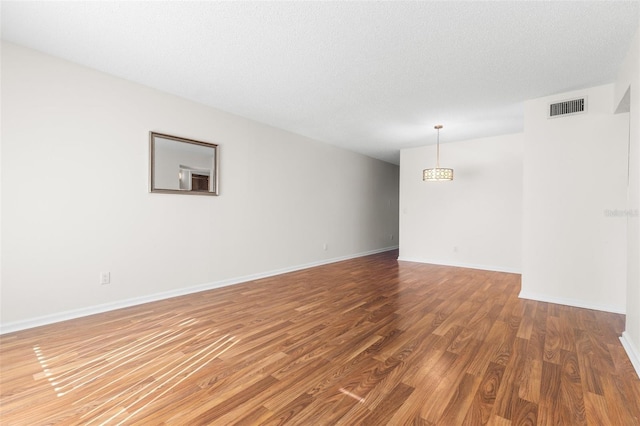 empty room featuring wood-type flooring and a textured ceiling