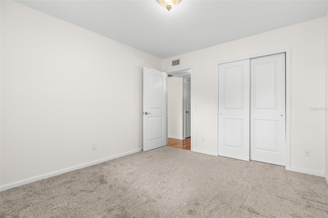 unfurnished bedroom featuring a closet, carpet floors, and a textured ceiling