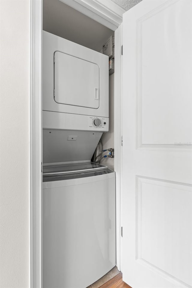 washroom featuring light hardwood / wood-style floors and stacked washer and clothes dryer