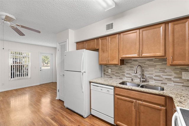 kitchen with white appliances, sink, ceiling fan, decorative backsplash, and light stone countertops