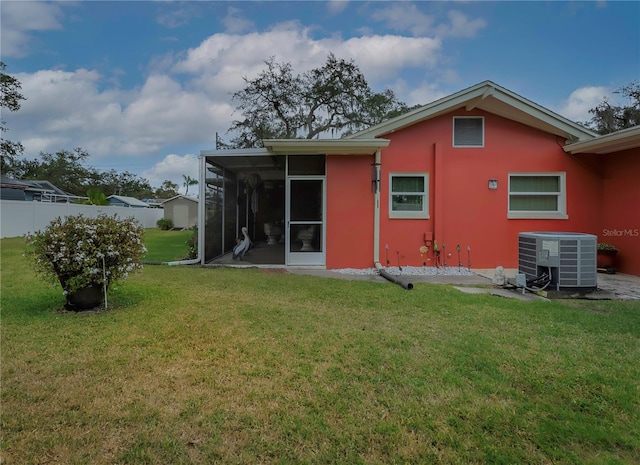 rear view of house featuring a lawn, a sunroom, and central AC unit