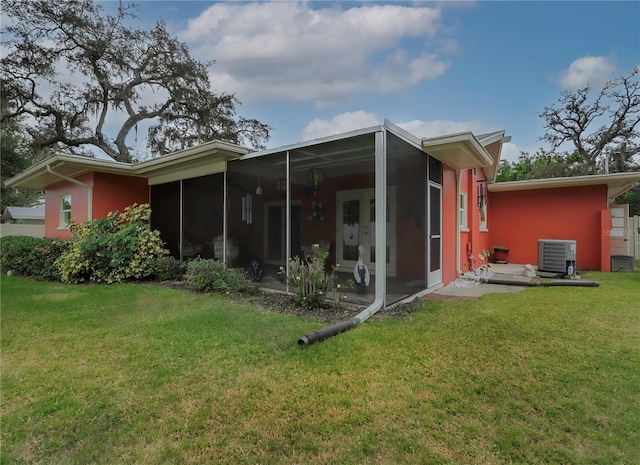 back of house featuring a sunroom, a yard, and central AC unit