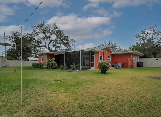 rear view of property with a sunroom, central AC unit, and a yard