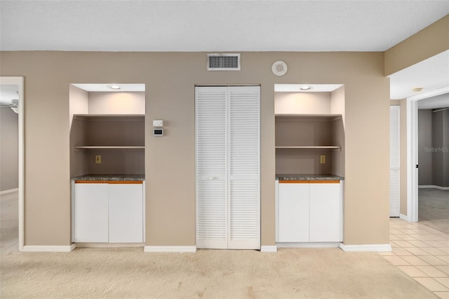 unfurnished bedroom with two closets and light colored carpet