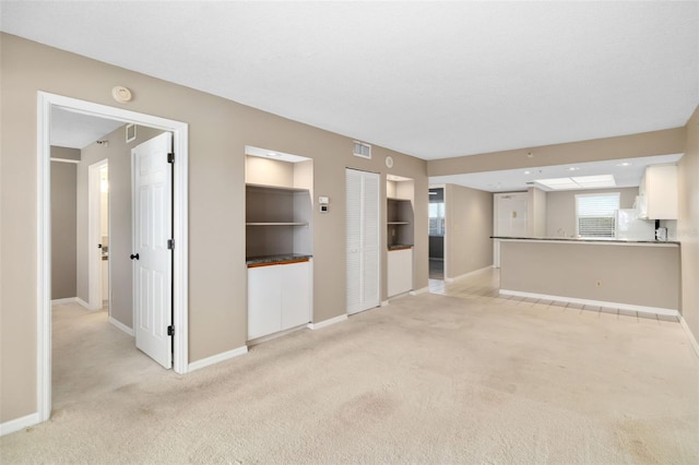 unfurnished living room featuring light colored carpet