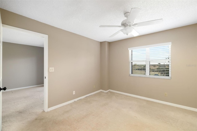 empty room featuring a textured ceiling, light colored carpet, and ceiling fan