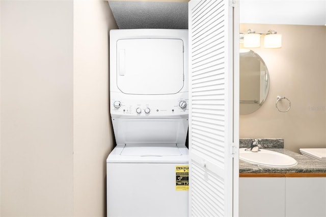 laundry room featuring a textured ceiling, stacked washing maching and dryer, and sink