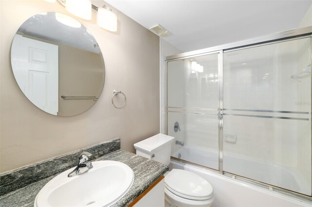 full bathroom featuring combined bath / shower with glass door, vanity, and toilet