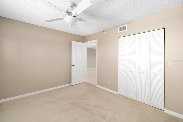 unfurnished bedroom featuring a textured ceiling, ceiling fan, light carpet, and a closet