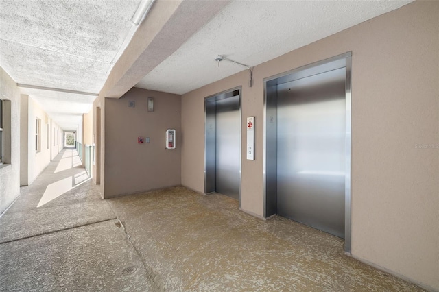 corridor with a textured ceiling and elevator