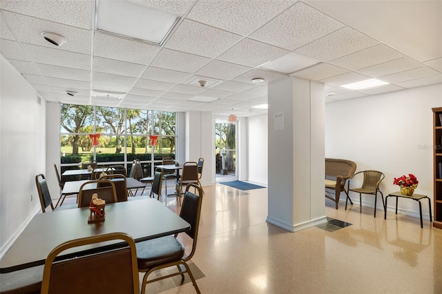 dining space featuring floor to ceiling windows and a drop ceiling