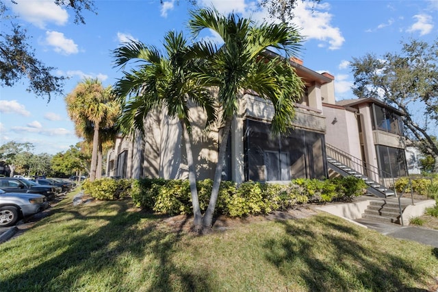 view of side of property featuring stairs, a yard, and stucco siding