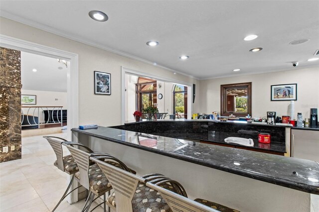 10265 Gandy Blvd N Unit 905, Saint Petersburg, FL 33702 - kitchen with ornamental molding, recessed lighting, dark stone counters, light tile patterned floors, and a kitchen bar