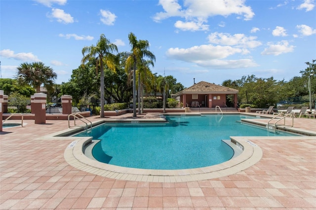 community pool with a patio area and fence