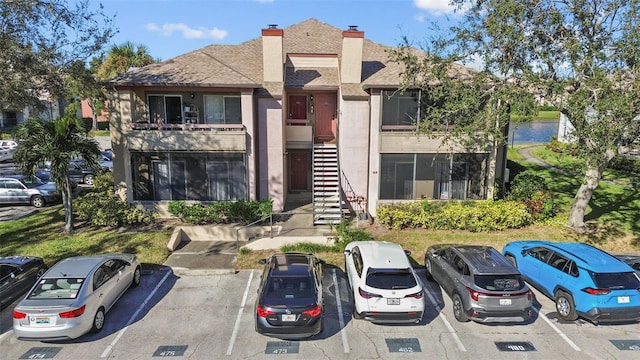 view of property with stairs and uncovered parking