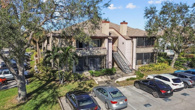 view of property featuring uncovered parking and stairway