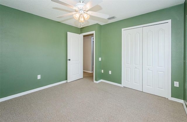 unfurnished bedroom featuring baseboards, visible vents, ceiling fan, carpet floors, and a closet