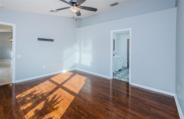 empty room featuring a ceiling fan, baseboards, visible vents, and wood finished floors