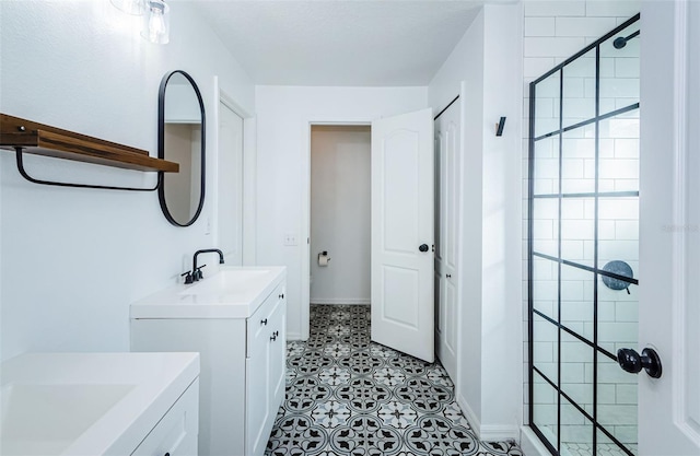 full bath featuring a sink, a shower stall, and two vanities