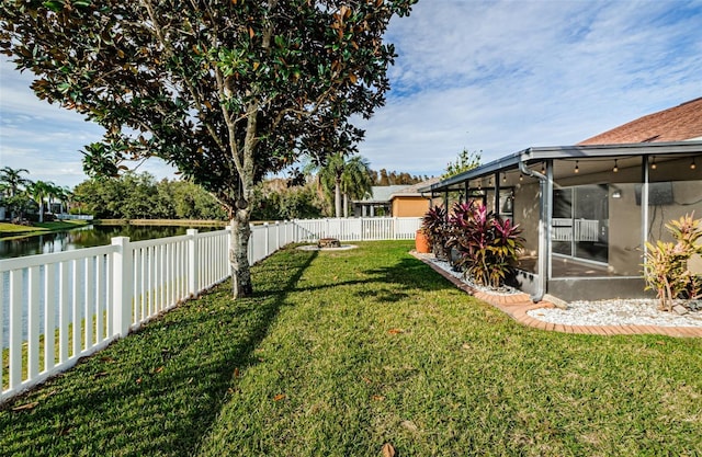 view of yard featuring a water view, a fenced backyard, and a sunroom