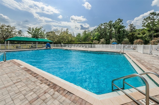 community pool with a patio and fence