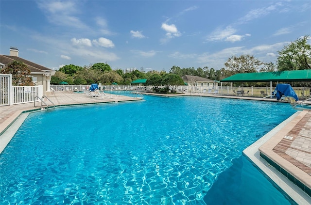 community pool with a patio area and fence