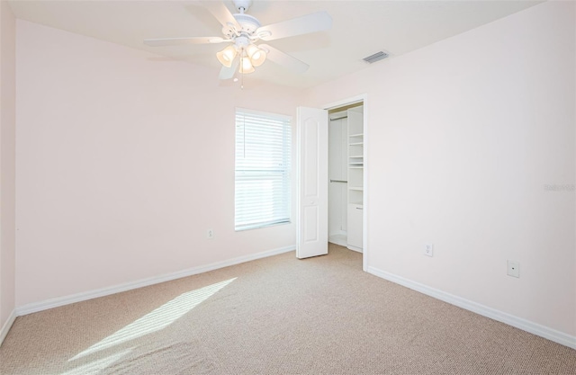 unfurnished bedroom featuring ceiling fan, light colored carpet, visible vents, baseboards, and a closet