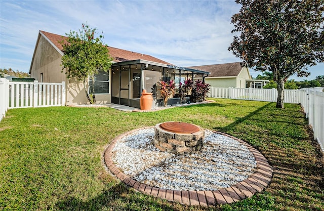 rear view of property with a fire pit, a lawn, a sunroom, a fenced backyard, and stucco siding