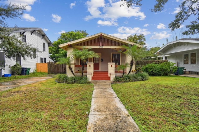 bungalow-style house featuring covered porch and a front yard