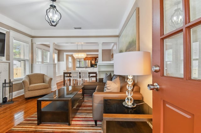 living room with decorative columns, wood-type flooring, and a chandelier