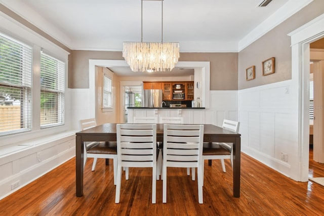 dining area with a chandelier, wood-type flooring, and ornamental molding