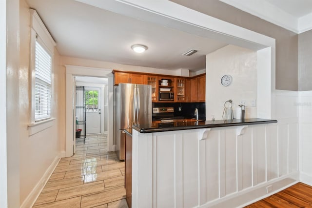 kitchen with backsplash, kitchen peninsula, and stainless steel appliances