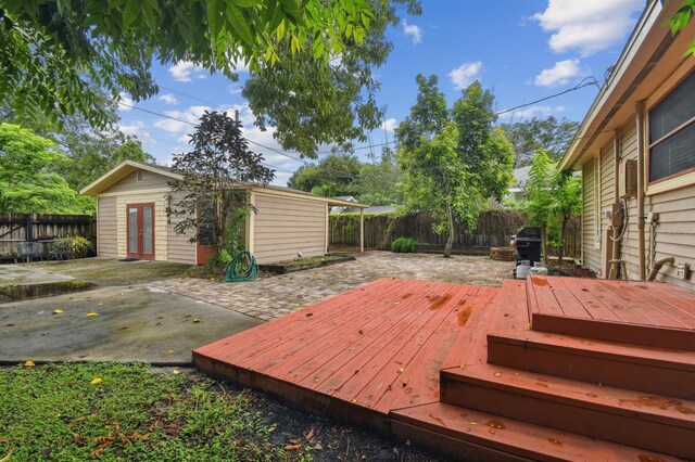 wooden deck featuring area for grilling, an outbuilding, and a patio