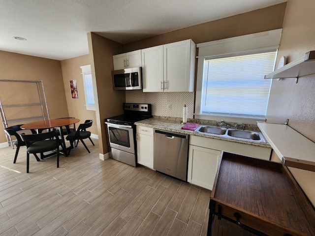 kitchen featuring light wood-type flooring, stainless steel appliances, a wealth of natural light, and sink