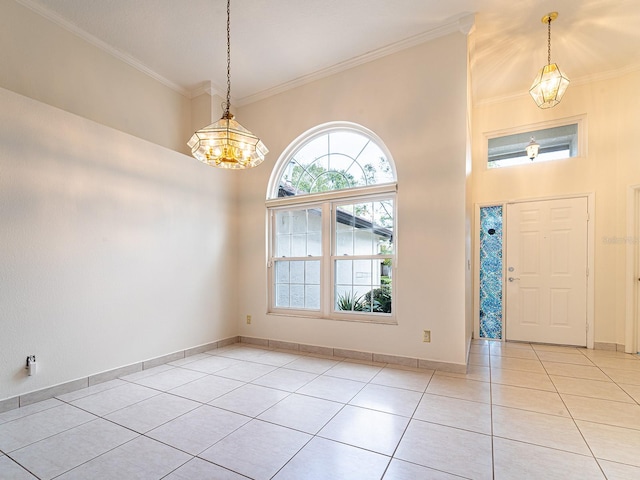 entryway featuring a towering ceiling, light tile patterned floors, a notable chandelier, and ornamental molding