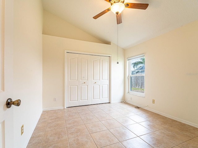 unfurnished bedroom with ceiling fan, a closet, light tile patterned floors, and vaulted ceiling