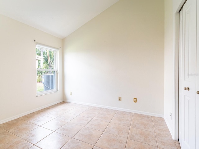 unfurnished room featuring light tile patterned flooring and vaulted ceiling