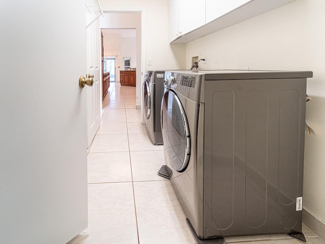 washroom featuring cabinets, light tile patterned floors, and washing machine and clothes dryer