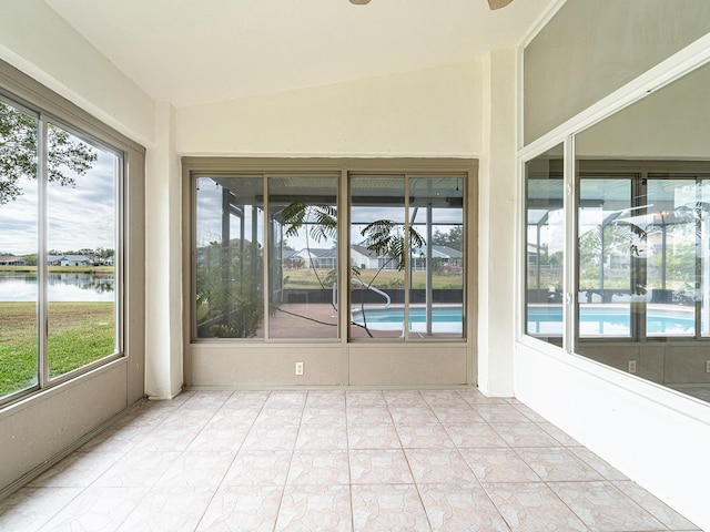 unfurnished sunroom featuring ceiling fan, a healthy amount of sunlight, a water view, and lofted ceiling