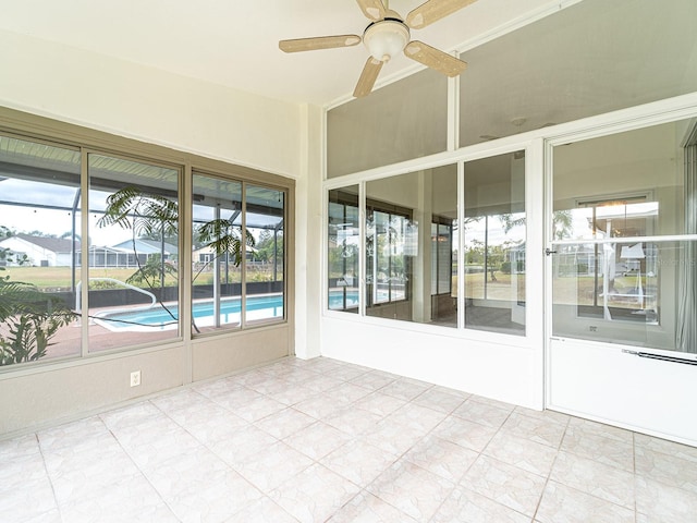 unfurnished sunroom featuring ceiling fan and plenty of natural light