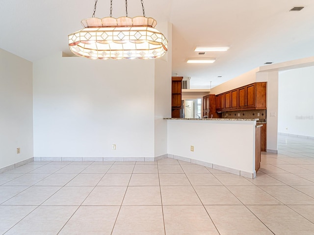 kitchen with kitchen peninsula, decorative backsplash, light tile patterned floors, and decorative light fixtures