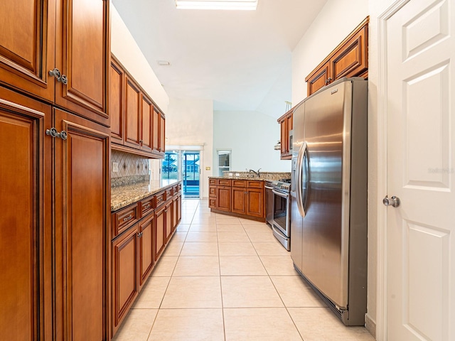 kitchen featuring stainless steel appliances, light stone counters, backsplash, vaulted ceiling, and light tile patterned flooring